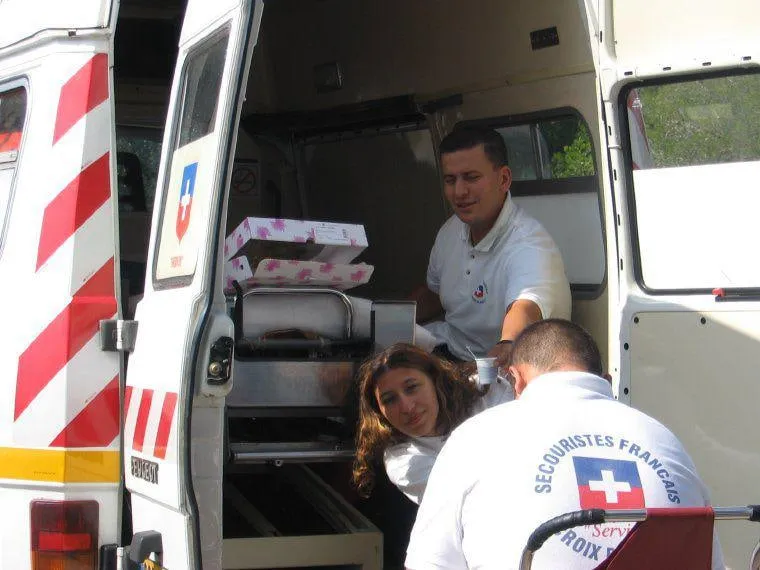 Deux secouristes prennent en charge une personne à l'arrière d'une ambulance.