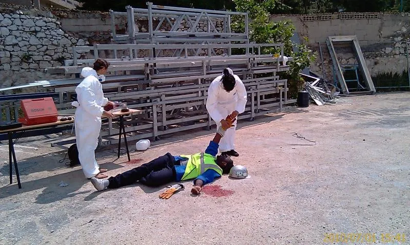 Deux stagiaires en combinaison blanche s'occupent d'une victime allongée au sol lors d'un exercice.
