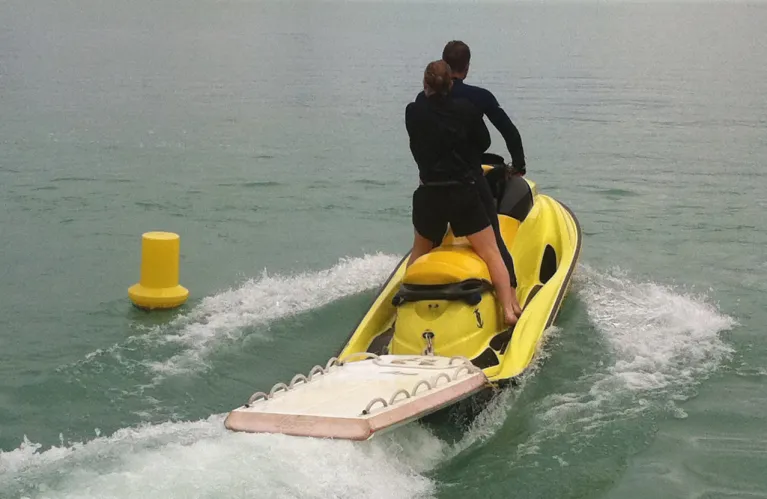 Un sauveteur pilote un jet de sauvetage qui tracte une planche jaune.