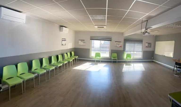 Salle Port Pin, chaises vertes alignées le long du mur.