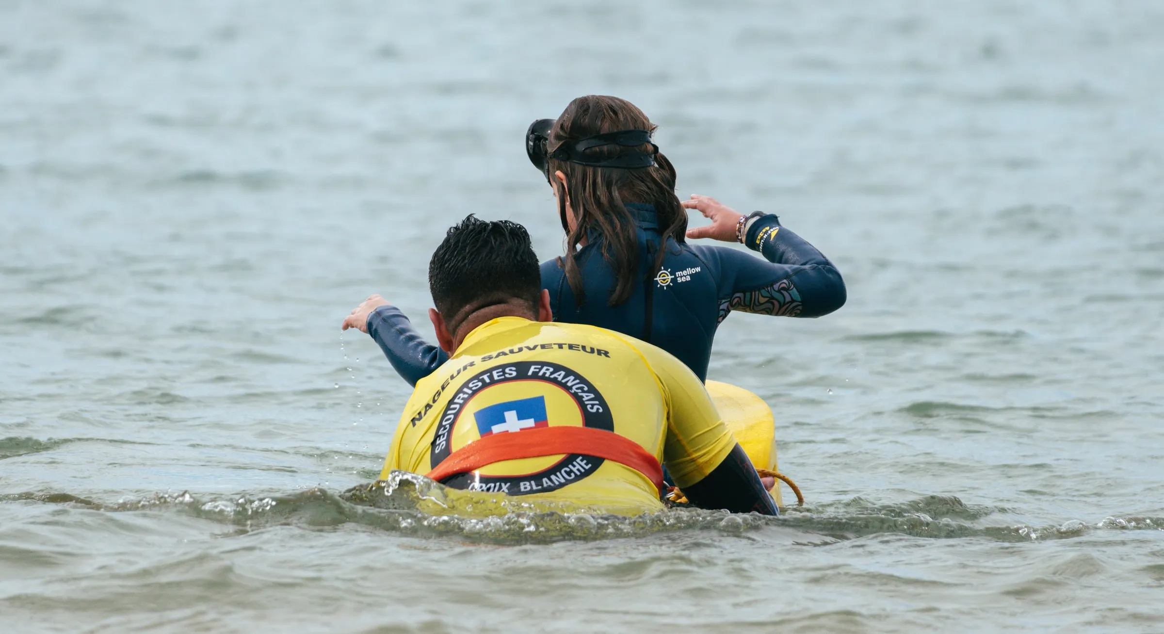 Un sauveteur et un enfant dans l'eau, accrochés à une bouée tube.